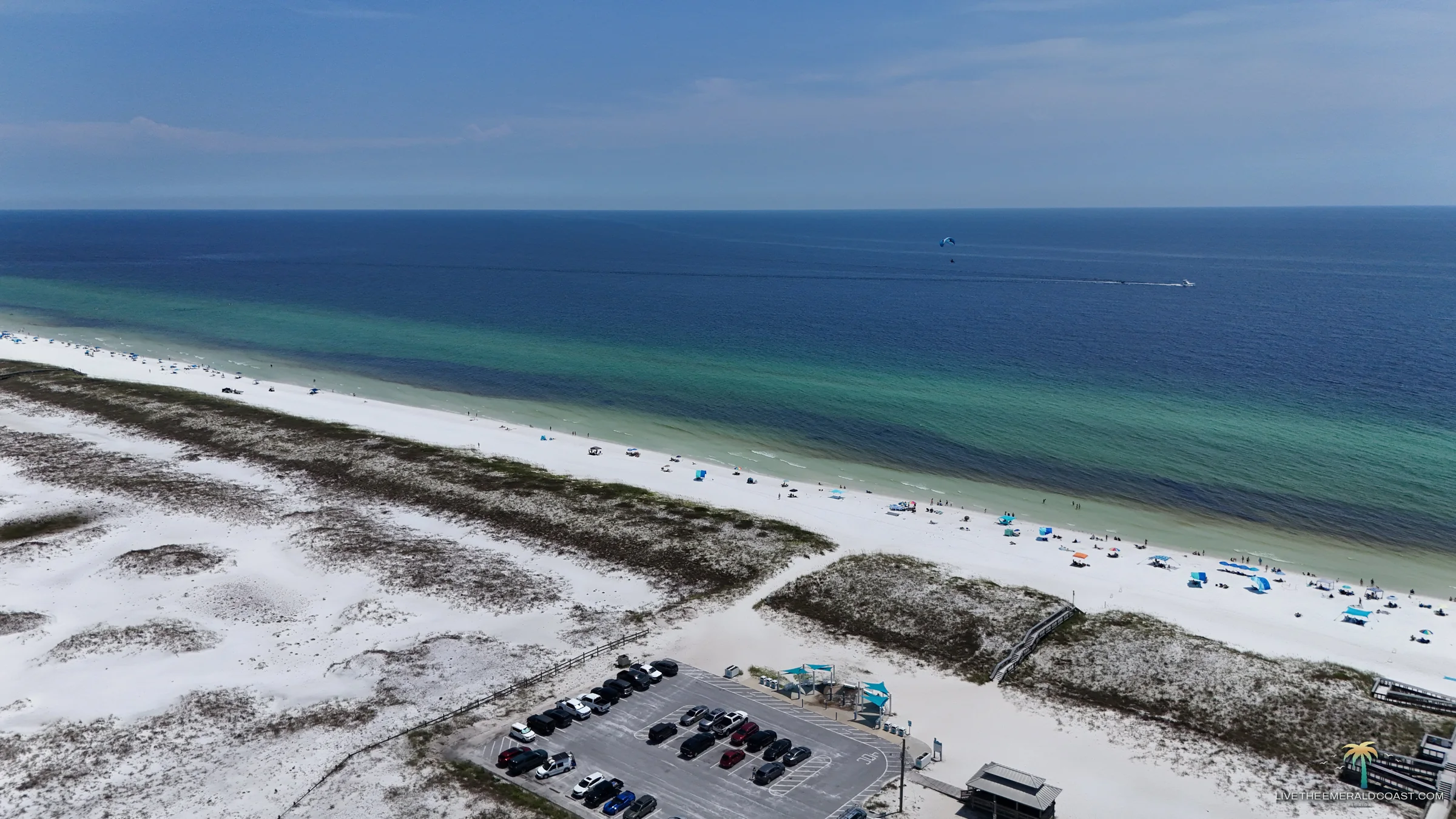 Aerial view of white sand dunes and the banded emerald water along the coastline at Navarre Beach, Florida