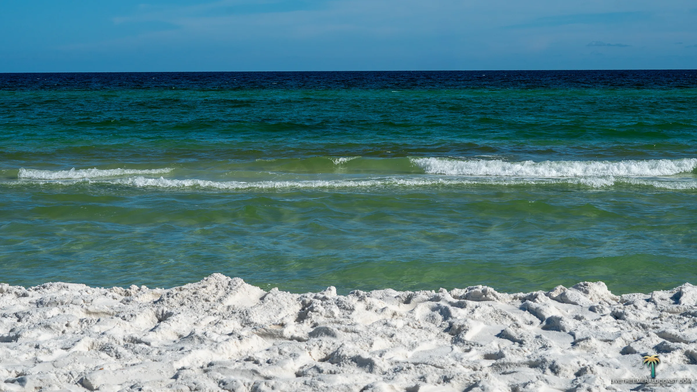 Clear emerald water breaking on the sugar white sand at Navarre Beach, Florida