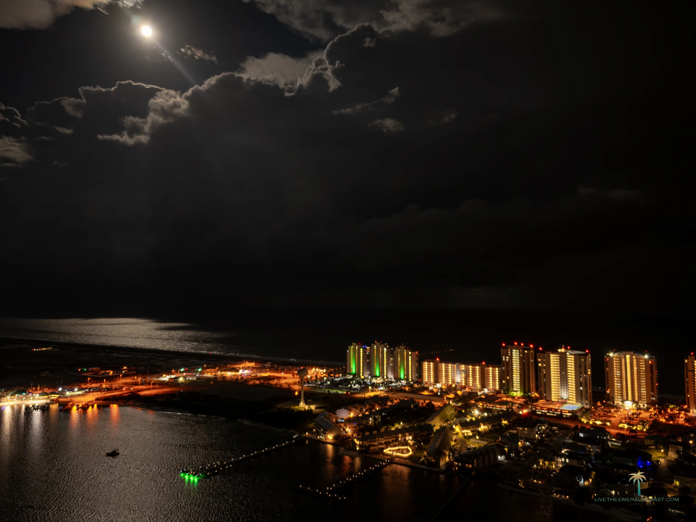 Full moon over Navarre Beach with moonlight running across the Gulf and the beach town lit along the shoreline